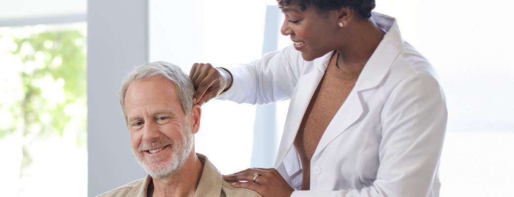 Image of senior male being fitted for a hearing aid by a female hearing care professional